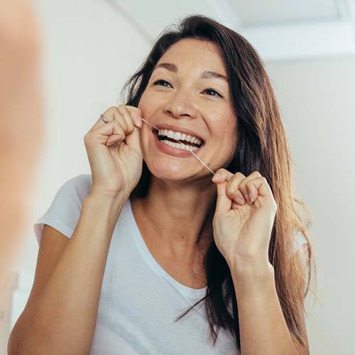 Woman flossing to prevent dental emergencies