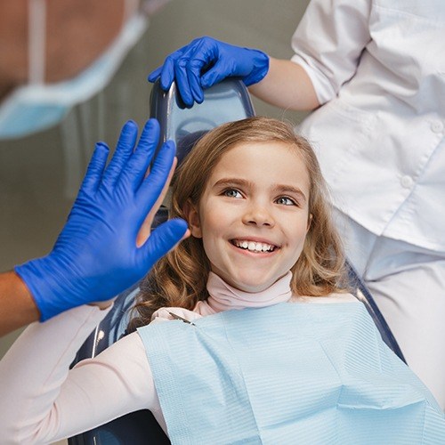 Smiling young girl giving dentist a high five